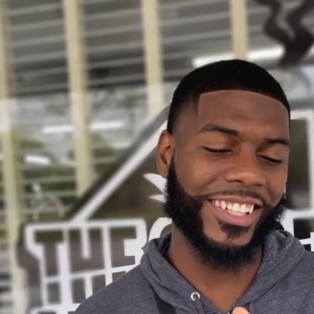 Client with a fresh lineup and beard smiling outside the shop